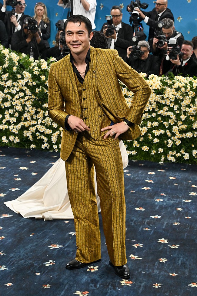Aktor Inggris berdarah Malaysia, Henry Golding tampil memukau dalam balutan setelan jas bernuansa gold dari Ozwald Boateng. Bintang film Crazy Rich Asia itu juga menambahkan koleksi perhiasan Cartier sebagai aksesoris. Foto: Getty Images