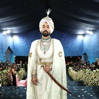 Diljit Dosanjh menampilkan warisan budayanya di Met Gala 2025. Aktor Bollywood itu memakai kostum busana rancangan Prabal Gurung yang terdiri dari sherwani bernuansa ivory, tehmat atau celana panjang kain dililit, hingga sorban berlapis permata. Tampak pula kirpan alias pedang berkepala singa di tangan kanannya. Foto: Getty Images