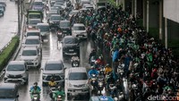 Pemotor memilih berteduh di bawah jalan layang Pancoran saat hujan deras turun. Aksi ini menutup sebagian jalan raya dan mengganggu lalu lintas.