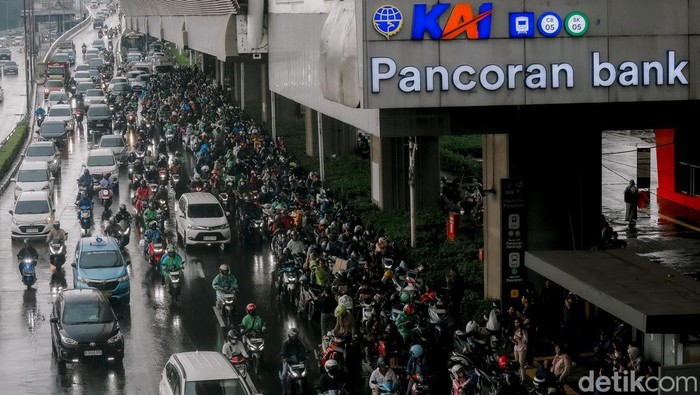 Sejumlah pemotor berteduh di bawah Stasiun LRT Pancoran saat hujan. Aksi ini sebabkan macet dan bisa kena sanksi denda hingga penjara sebulan.
