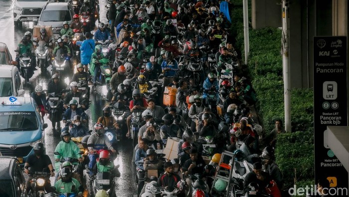 Sejumlah pemotor berteduh di bawah Stasiun LRT Pancoran saat hujan. Aksi ini sebabkan macet dan bisa kena sanksi denda hingga penjara sebulan.