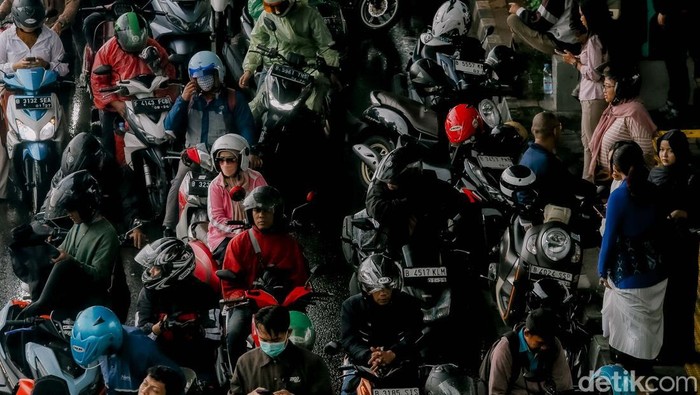 Sejumlah pemotor berteduh di bawah Stasiun LRT Pancoran saat hujan. Aksi ini sebabkan macet dan bisa kena sanksi denda hingga penjara sebulan.