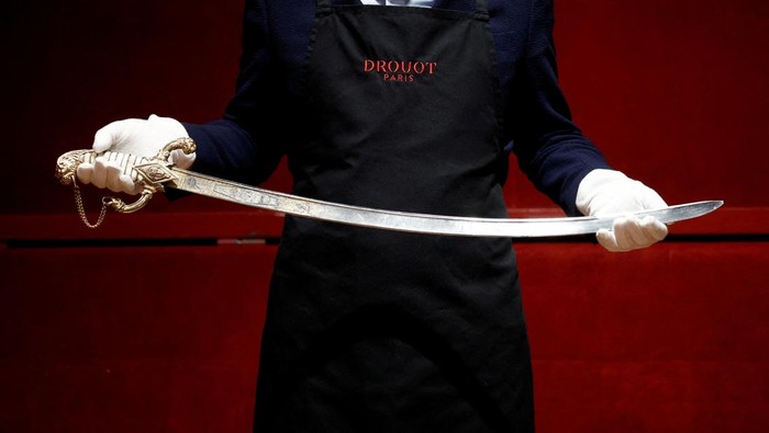 Penampakan Pedang Napoleon yang Bakal Dilelang di Paris A Drouot employee holds the saber that Napoleon ordered for his personal use from the arquebusier Nicolas-Noel Boutet in 1802 before its auction at Drouot auction house in Paris, France, April 24, 2025. REUTERS/Benoit Tessier TPX IMAGES OF THE DAY