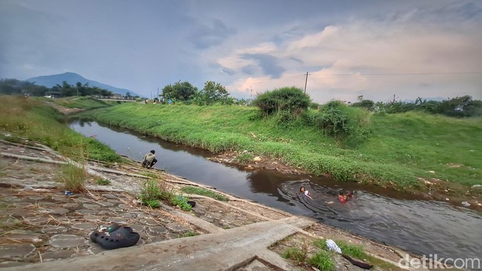 Sejumlah anak-anak tengah berenang di aliran air sungai berwarna hitam