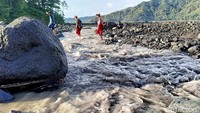 Para siswa terpaksa melepas sepatu agar tidak basah saat menyeberangi aliran lahar. Hal ini lantaran banjir lahar Gunung Semeru menyebabkan Jembatan Limpas tertimbun material banjir lahar.