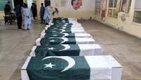 Warga berkumpul di depan deretan peti jenazah sebelum prosesi pemakaman di sebuah sekolah Islam di Bahawalpur, Pakistan, Rabu (7/5/2025). Peti jenazah berselimut bendera nasional Pakistan. (Mahmood Zaheer/Reuters)
