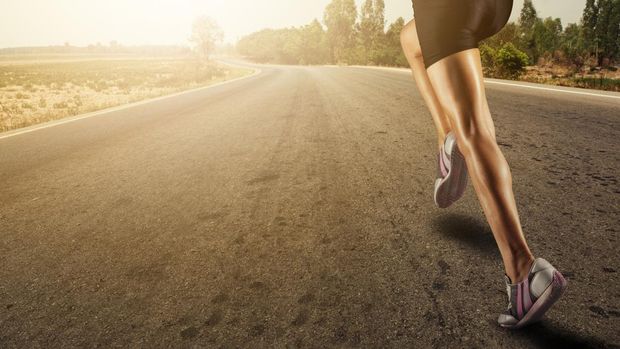 Sports background. Runner feet running on road closeup on shoe.flare light