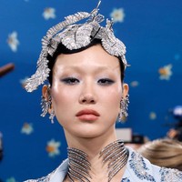 Model asal Korea Selatan, Sora Choi, tampil seperti kristal berjalan dalam balutan Swarovski dari ujung kepala hingga kaki. Jaket biru es dan rok berbulu dihiasi ikat pinggang kristal berbentuk bulu burung, yang selaras dengan hiasan kepala, anting, dan choker Swarovski-nya. (Foto: Taylor Hill/Getty Images)