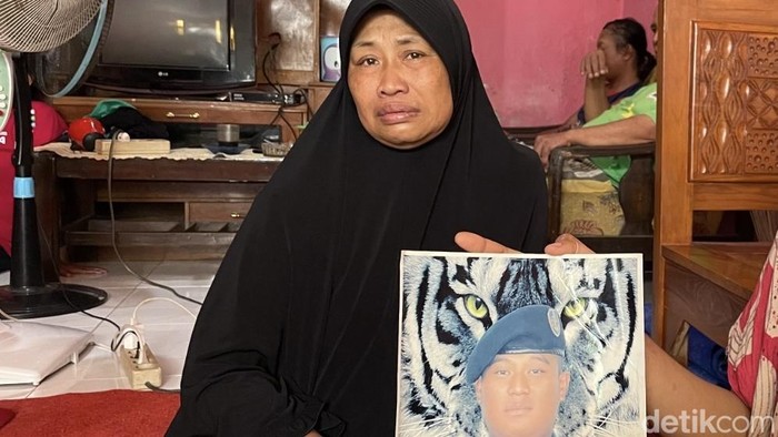Ibunda Rizal Sampurna tengah memegang foto putranya saat mengenakan seragam sekolah pelayaran.