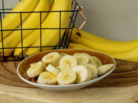 Fresh bananas and bananas cut into pieces in a bowl on the table - stock photo