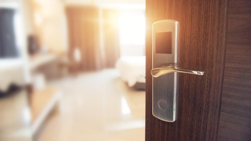 Opened door of hotel room in morning with copy space, sunlight effect.