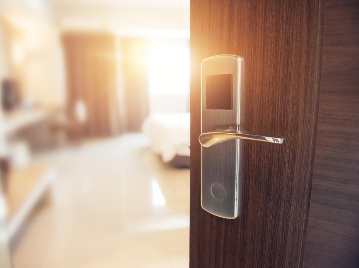 Opened door of hotel room in morning with copy space, sunlight effect.