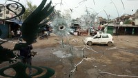 Warga melintas di depan bus yang berlubang akibat penembakan di Poonch dekat Garis Kontrol (LoC) antara India dan Pakistan, Kamis (8/5/2025).