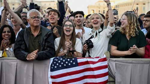 People holding a U.S. flag react as newly elected Pope Leo XIV, Cardinal Robert F. Prevost of the U.S., appears on the balcony of St. Peters Basilica at the Vatican, May 8, 2025.   REUTERS/DYLAN MARTINEZ