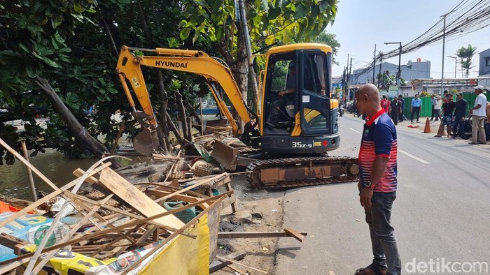 Petugas gabungan dari pemerintah daerah Kota Bekasi melakukan penertiban lapak pedagang kaki lima di sepanjang bantaran Kali Rawa Tembaga, Jalan Kemakmuran, Jumat (9/5/2025). Penertiban dilakukan secara bertahap dengan menyasar kios-kios dan bangunan semi permanen yang berdiri di atas saluran air.