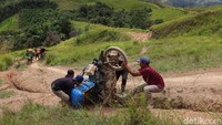 Tukang ojek membantu memperbaiki posisi motor rekannya yang terbalik saat melewati jalan menanjak di Kecamatan Seko, Kabupaten Luwu Utara, Sulawesi Selatan.