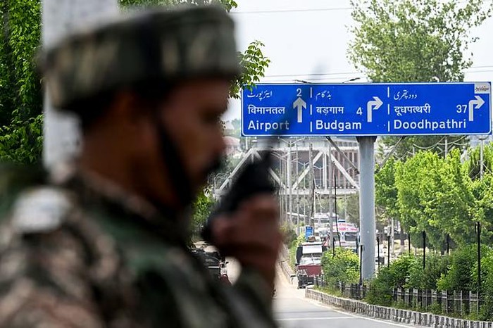 Seorang personel paramiliter India menggunakan transceiver genggam berjaga di sepanjang jalan menuju bandara internasional di Srinagar, Sabtu, 10 Mei 2025.