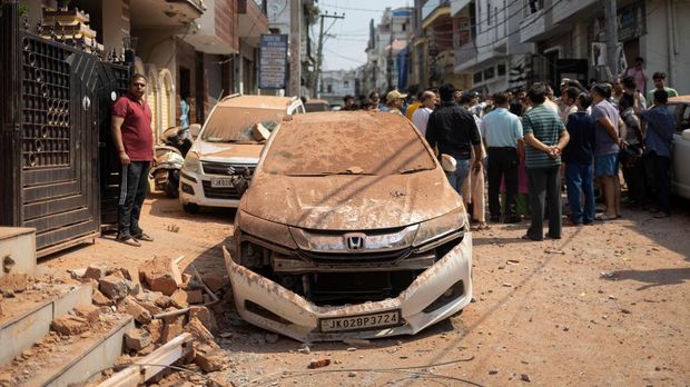 People stand next to a damaged vehicle in a neighbourhood, following Pakistan's military operation against India, in Rehari, Jammu, May 10, 2025. REUTERS/Adnan Abidi