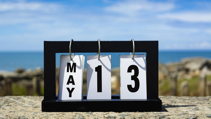 May 13 calendar date text on wooden frame with blurred background of ocean. Calendar date concept.