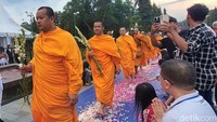 Umat Buddha mengiringi para biksu dengan sikap hormat dan berdoa sepanjang jalan menuju tangga candi.