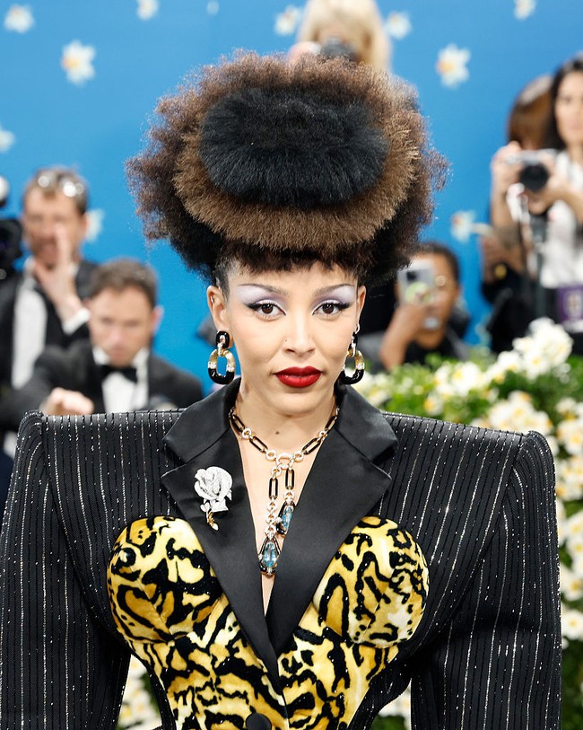 Doja Cat memadukan bodysuit rancangan Marc Jacobs dengan perhiasan dari David Webb. Ia mengenakan anting lingkar hitam-emas bertakhtakan berlian, kalung paper clip dengan aquamarine dan berlian, serta bros mawar berlian di kerah jas. Serangkaian cincin berlian dari rumah mode yang sama menyempurnakan tampilannya. (Foto: Taylor Hill/Getty Images)