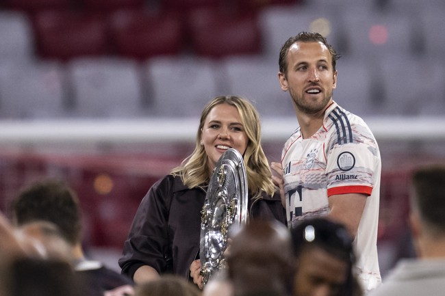 MUNICH, GERMANY - MAY 10: Harry Kane of FC Bayern Muenchen celebrates his teams league title victory with wife Katie Goodland while holding the Meisterschale tropy after Bayern Muenchens 2-0 victory in the Bundesliga match between FC Bayern München and Borussia Mönchengladbach at Allianz Arena on May 10, 2025 in Munich, Germany. (Photo by Kevin Voigt/GettyImages)