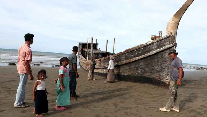 Wisatawan berswafoto dengan latar kapal kayu yang pernah digunakan pengungsi Rohingya di pantai Mata Ie Sepeung, Laweung, Kabupaten Pidie, Aceh, Sabtu (10/5/2025). Kapal kayu yang terdampar pada 14 November 2023 dengan membawa 169 orang pengungsi Rohingya itu telah menjadi daya tarik wisata yang ramai dikunjungi bagi wisatawan. ANTARA FOTO/Irwansyah Putra