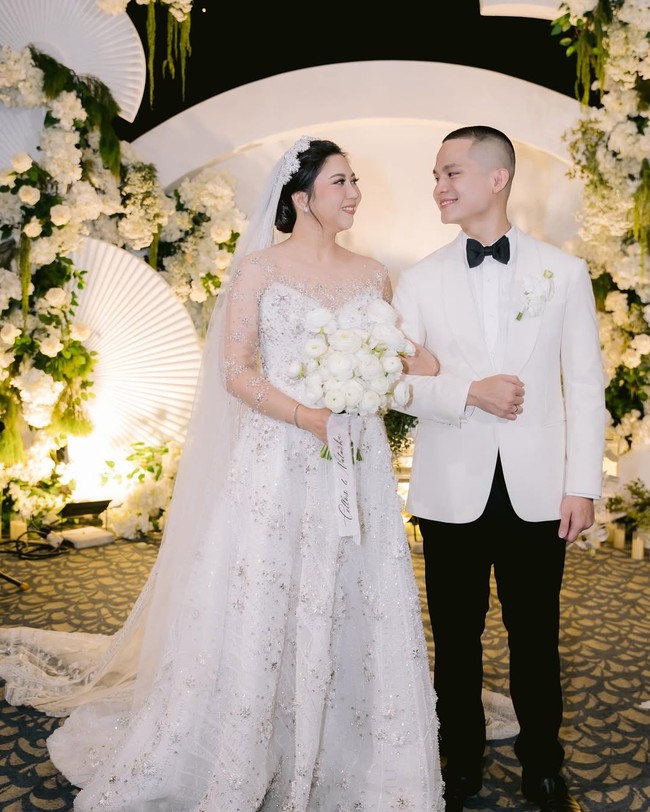 Cellos dan Natasha Putri tampil serasi mengenakan busana putih pada saat pemberkatan pernikahan. Cellos memakai jas dan dasi kupu-kupu dari Wonghang Tailor. Sedangkan Natasha mengenakan gaun rancangan Soko Wiyanto. Foto: Dok. Instagram by.hilda
