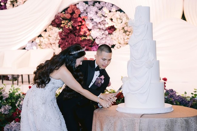 Dinding belakang pelaminan Cellos dan Natasha Putri dihiasi bunga-bunga artificial atau segar dalam palet warna ungu, pink pastel, merah marun, dan lavender,  Foto: Dok. Instagram by.hilda