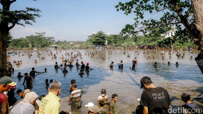 Ratusan warga tampak antusias mengikuti kegiatan Ngubek Empang yang digelar di kawasan Pengasinan, Depok, pada Minggu (11/5). Tradisi yang telah mengakar sejak zaman orang tua dahulu ini kembali diadakan sebagai bagian dari rangkaian acara Lebaran Depok 2025.