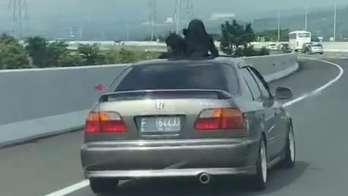 Dua Bocah Mengeluarkan Sebagian Tubuh Lewat Sunroof Mobil di Jalan Tol
