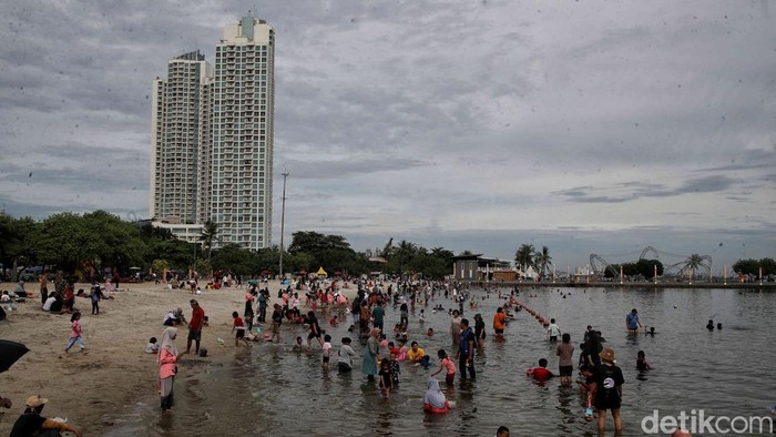 Pengunjung menikmati suasana Pantai Ancol, Jakarta Utara, Senin (12/2025).
