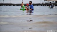 Selain menikmati panorama pantai, para wisatawan juga memanfaatkan momen ini untuk berenang, bermain pasir, dan mengabadikan momen bersama keluarga.