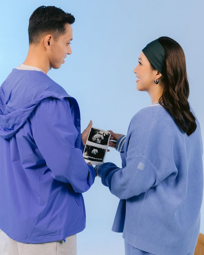 Latar biru muda, jaket hoodie, serta foto hasil USG memberikan kesan penuh harapan. Visual ini cocok untuk kamu yang menginginkan tema maternity yang youthful dan lembut. Foto: Instagram/@ribkasugiarto