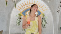 Di kafe tema pantai, Dinda melengkapi momennya dengan outfit tema summer yang cerah. Ia juga memegang segelas jus dengan garnish berupa irisan jeruk. Foto: Instagram dindakirana.s