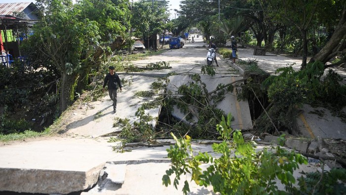 Petugas melintasi jalan yang amblas di kawasan Jalan HAM Rifaddin, Loa Janan Ilir, Samarinda Seberang, Samarinda, Kalimantan Timur, Selasa (13/5/2025). Menurut petugas Balai Besar Pelaksanaan Jalan Nasional (BBPJN) Kalimantan Timur, jalan nasional akses utama penghubung Samarinda-Balikpapan itu terputus sekitar 15 meter pada Senin (12/5) malam sekitar pukul 21.15 WITA akibat curah hujan yang tinggi. ANTARA FOTO/M Risyal Hidayat/YU