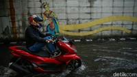 Beberapa pengendara motor terpaksa melawan arus air dengan mengangkat kaki agar tidak basah.