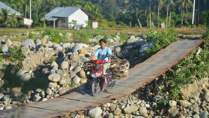 Warga menggunakan sepeda motor melewati jembatan darurat di Nagari Koto Rawang, Kecamatan IV Jurai, Pesisir Selatan, Sumatera Barat, Kamis (15/5/2025). Jembatan darurat yang dibuat pasca banjir bandang tahun lalu itu masih digunakan untuk akses utama bagi masyarakat setempat, walaupun kondisinya membahayakan. ANTARA FOTO/Iggoy el Fitra/Spt.