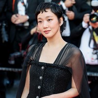 Satu detail yang mencuri perhatian di bagian atas adalah kancing perak yang diletakkan tepat di tengah, sebagai aksen sederhana. Namun, elemen yang paling menonjol dari look ini adalah cape panjang yang tersemat di bagian bahu. Cape transparan ini panjang menyentuh lantai, menciptakan efek dramatis yang bergerak seiring langkah sang aktris.  Foto: Getty Images/Lyvans Boolaky