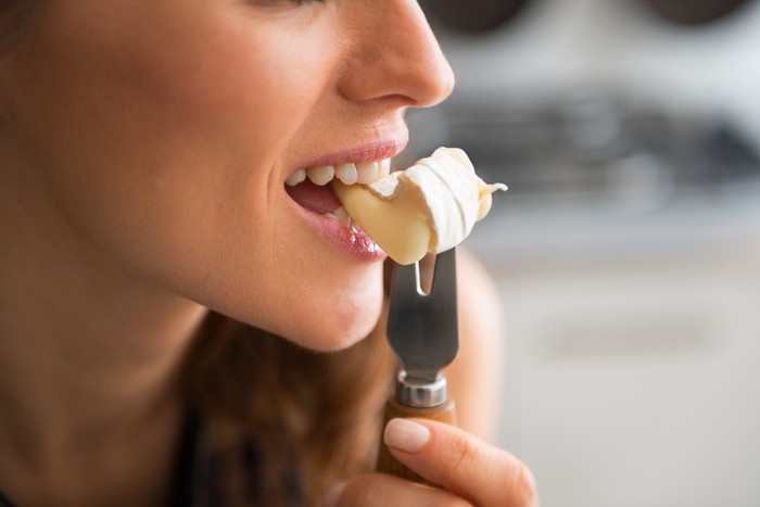 Closeup on young woman eating camembert