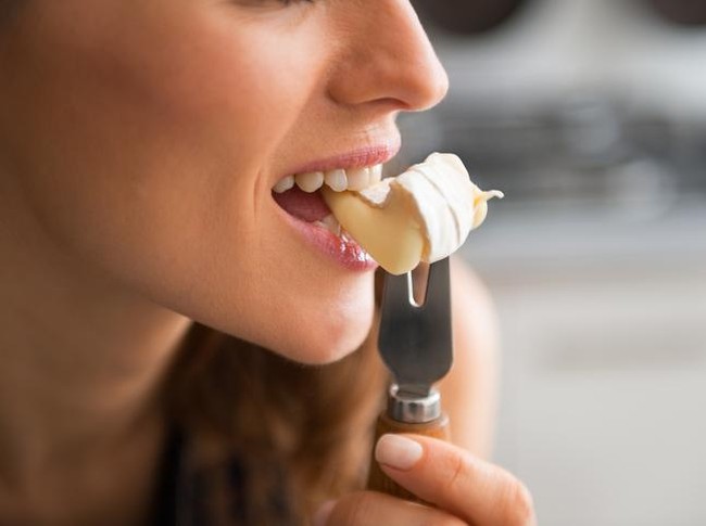 Closeup on young woman eating camembert