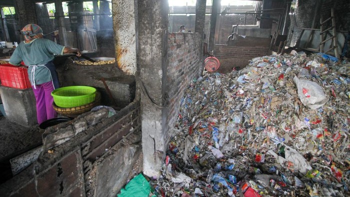 Pekerja menggoreng tahu di salah satu pabrik tahu yang menggunakan sampah plastik sebagai bahan bakar di Tropodo, Krian, Sidoarjo, Jawa Timur, Kamis (15/5/2025). Pabrik tahu di wilayah tersebut menggunakan sampah plastik dan spon karet sebagai bahan bakar karena harganya yang murah meski asap hasil pembakaran sampah plastik bisa mencemari udara. ANTARA FOTO/Umarul Faruq/bar