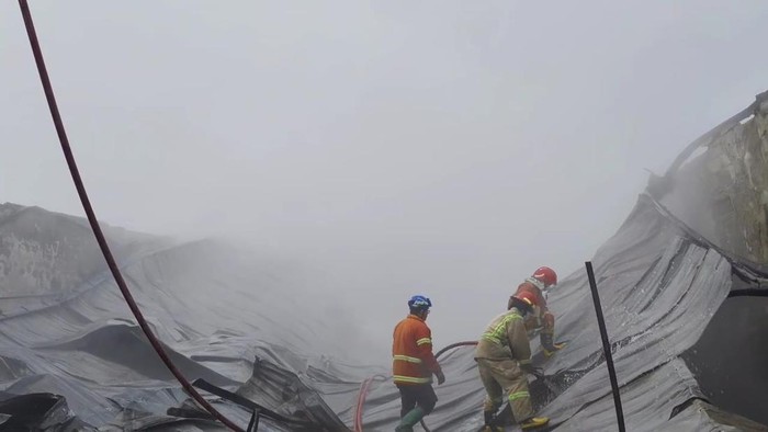 Proses pemadaman kebakaran gudang spons di Jombang.