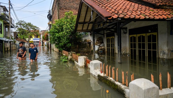 Siswi SMP melakukan swafoto saat melintasi banjir yang menggenangi permukiman di Kampung Bojongasih, Dayeuhkolot, Kabupaten Bandung, Jawa Barat, Jumat (16/5/2025). Hujan yang mengguyur Bandung Raya pada Kamis (15/5) mengakibatkan beberapa kampung di Desa Dayeuhkolot terendam air luapan Sungai Citarum setinggi 40 cm hingga 1 meter. ANTARA FOTO/Raisan Al Farisi/tom.