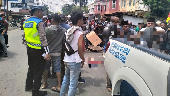 Polisi dibantu warga saat mengevakuasi jasad wanita parubaya yang tewas usai terlindas truk muatan semen.