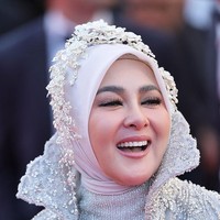 Hijab putih yang dikenakannya dihias dengan mahkota floral beaded karya desainer aksesori Rinaldy Yunardi. Untuk melengkapi penampilannya, Syahrini membawa clutch kulit bertekstur buaya, serta cincin statement di jari-jarinya yang mempertegas aura glamor. Foto: Getty Images/Vittorio Zunino Celotto