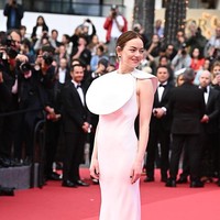 Emma Stone menebar pesonanya dalam balutan column dress putih Louis Vuitton yang dilengkapi kerah berbentuk piringan lebar yang disebut-sebut terinspirasi dari seragam kafe tradisional Prancis. Desain serupa pernah diperlihatkan dalam koleksi musim gugur 2023 Vuitton rancangan  Nicolas Ghesquière, direktur kreatif lini busana wanita rumah mode Prancis tersebut. (Foto: Stephane Cardinale/Corbis via Getty Images)