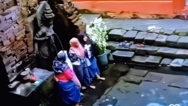 Aksi wisatawan foto di depan arca Petirtaan Belahan Pasuruan saat ada orang ritual yang viral di media sosial