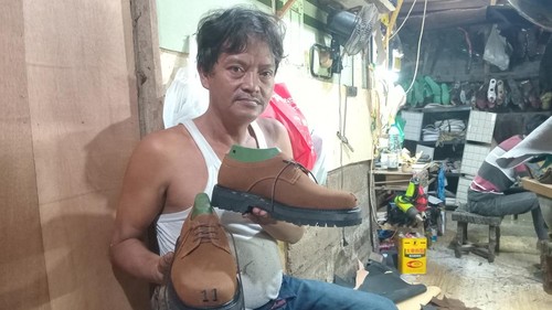 Budiono menunjukkan sepasang sepatu karyanya, Sabtu (3/5/2025). Budiono adalah pemilik bengkel sepatu Iwan Shoes di Jalan Mataram Gang Seruni Nomor 22, Kecamatan Kuta, Badung, yang digandrungi turis. (Aryo Mahendro/detikBali)