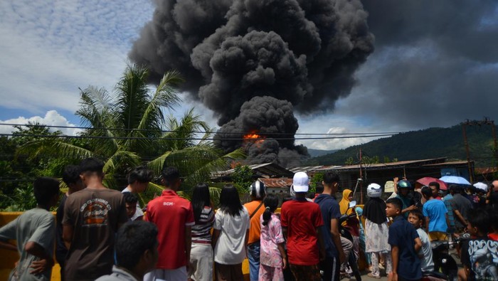 Warga melihat api membakar pabrik karet PT Teluk Luas, di Jalan Bypass Padang, Sumatera Barat, Minggu (18/5/2025). Kebakaran terjadi sekitar pukul 13.00 WIB itu membakar pabrik karet disertai dengan ledakan yang lokasinya berada tidak jauh dari pemukiman penduduk. ANTARA FOTO/Iggoy el Fitra/foc.